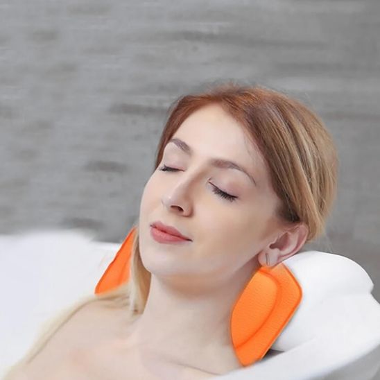femme se relaxant dans baignoire avec coussin de bain orange