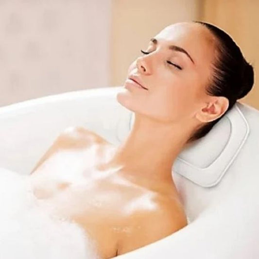 femme se relaxant dans baignoire avec coussin de bain blanc
